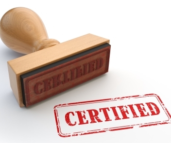 Ein Holzstempel mit der Aufschrift "CERTIFIED" in roter Farbe, daneben ein roter Stempelabdruck des Wortes "CERTIFIED".