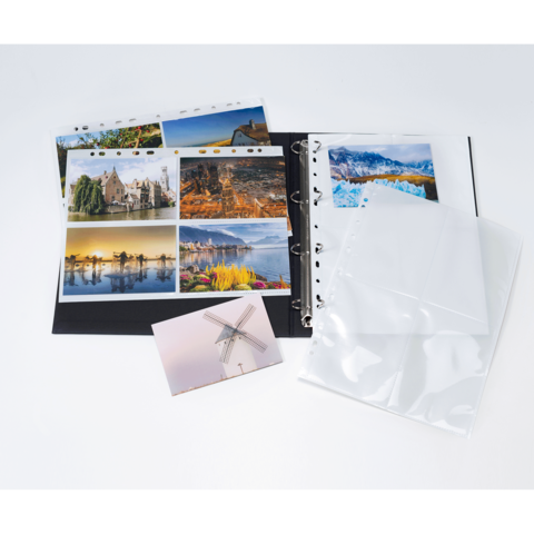 Ein Fotoalbum mit mehreren Seiten, die Landschafts- und Architekturaufnahmen zeigen, sowie leere Klarsichthüllen und eine Postkarte.