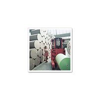 Eine Frau bedient einen Gabelstapler in einer Lagerhalle, um große Papierrollen zu bewegen, während weitere Rollen im Hintergrund gestapelt sind.