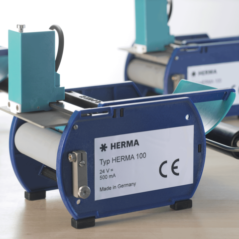 HERMA Typ 100 Etikettiermaschine, blau und grau, mit technischen Spezifikationen auf dem Gehäuse, hergestellt in Deutschland.