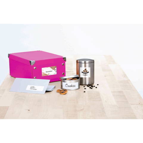 Eine pinke Box, ein Keksbehälter mit der Aufschrift "Cookies", eine Kaffeekanne und ein Umschlag auf einem Holztisch.