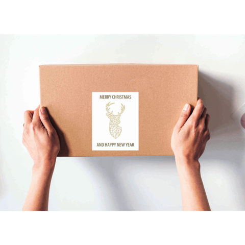 Eine Person hält ein braunes Paket mit einem Aufkleber, der "Frohe Weihnachten und ein glückliches neues Jahr" zeigt, sowie einem Hirschmotiv.