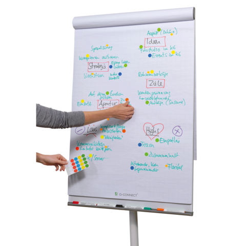 Eine Hand platziert einen roten Aufkleber auf einem Planer, umgeben von bunten Aufklebern und Stiften.