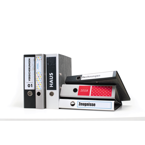 Eine Gruppe von Aktenordnern in verschiedenen Farben, beschriftet mit "Versicherungen", "Haus", "Rechnungen" und "Zeugnisse".