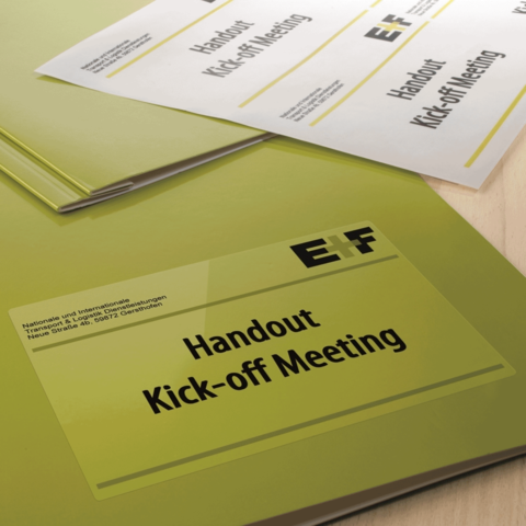 Handouts für ein Kick-off-Meeting in einer grünen Mappe, mit dem Titel "Handout Kick-off Meeting" deutlich sichtbar.