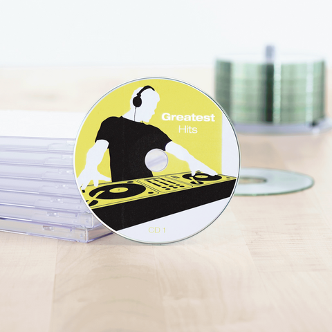 Texto: "CD titulada 'Grandes Éxitos', colocada sobre una mesa, rodeada de estuches de CD vacíos.