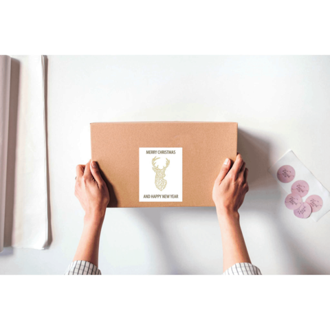 Eine Person hält ein braunes Paket mit einem Aufkleber, der "Frohe Weihnachten und ein gutes neues Jahr" zeigt.
