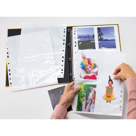 Ein Fotoalbum mit mehreren leeren und gefüllten Hüllen, in denen Bilder von Kindern mit Partyhüten und bunten Accessoires aufbewahrt werden.